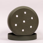 Nærbillede af grøn Seedling urtepotteskjuler Ø11cm på siden i drypbakken, med fokus på drænhullerne i bundens midte.