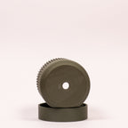 Nærbillede af grøn Seedling urtepotteskjuler Ø6cm, lagt på siden i drypbakken på hvid baggrund, der tydeligt viser drænhullerne i bunden.