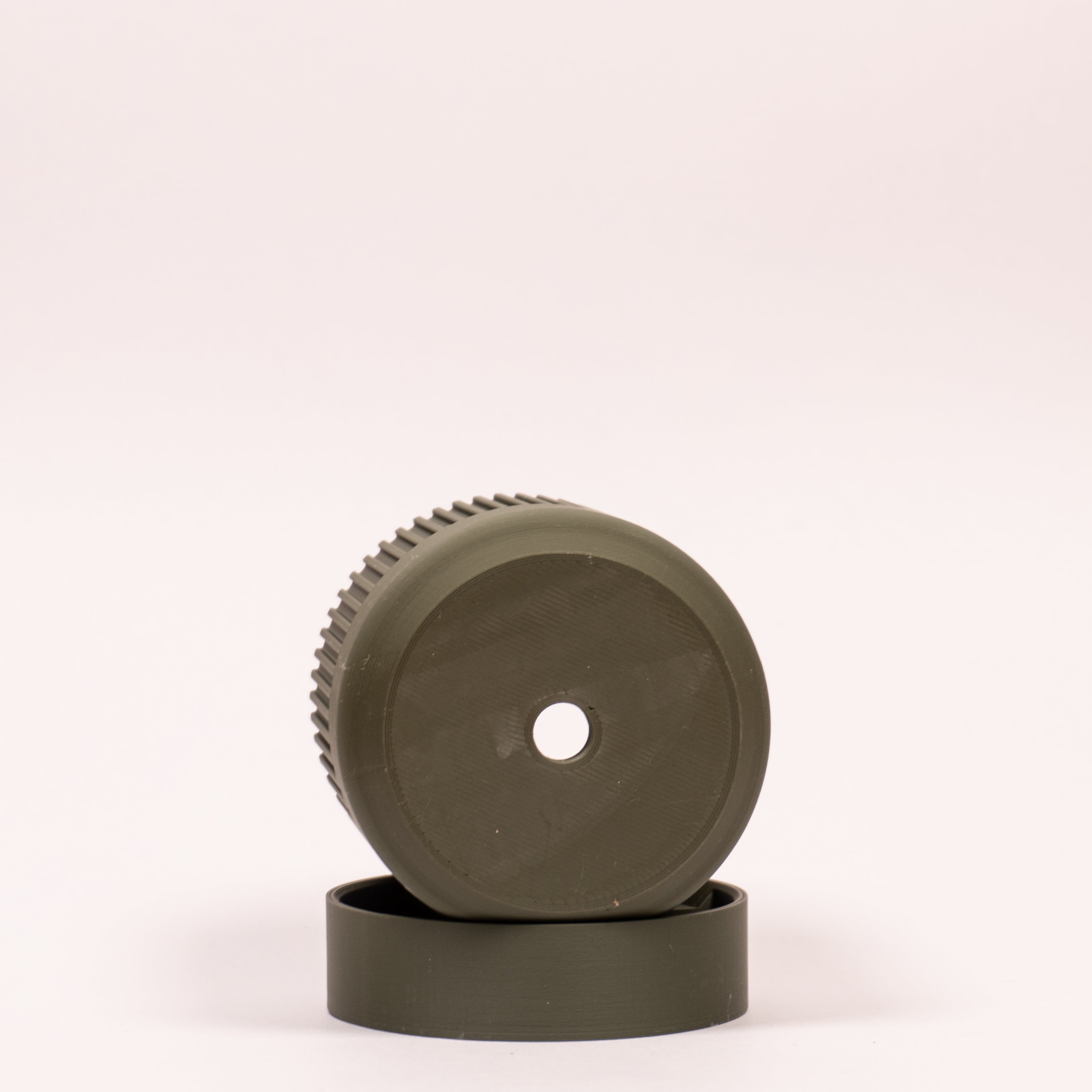 Nærbillede af grøn Seedling urtepotteskjuler Ø6cm, lagt på siden i drypbakken på hvid baggrund, der tydeligt viser drænhullerne i bunden.