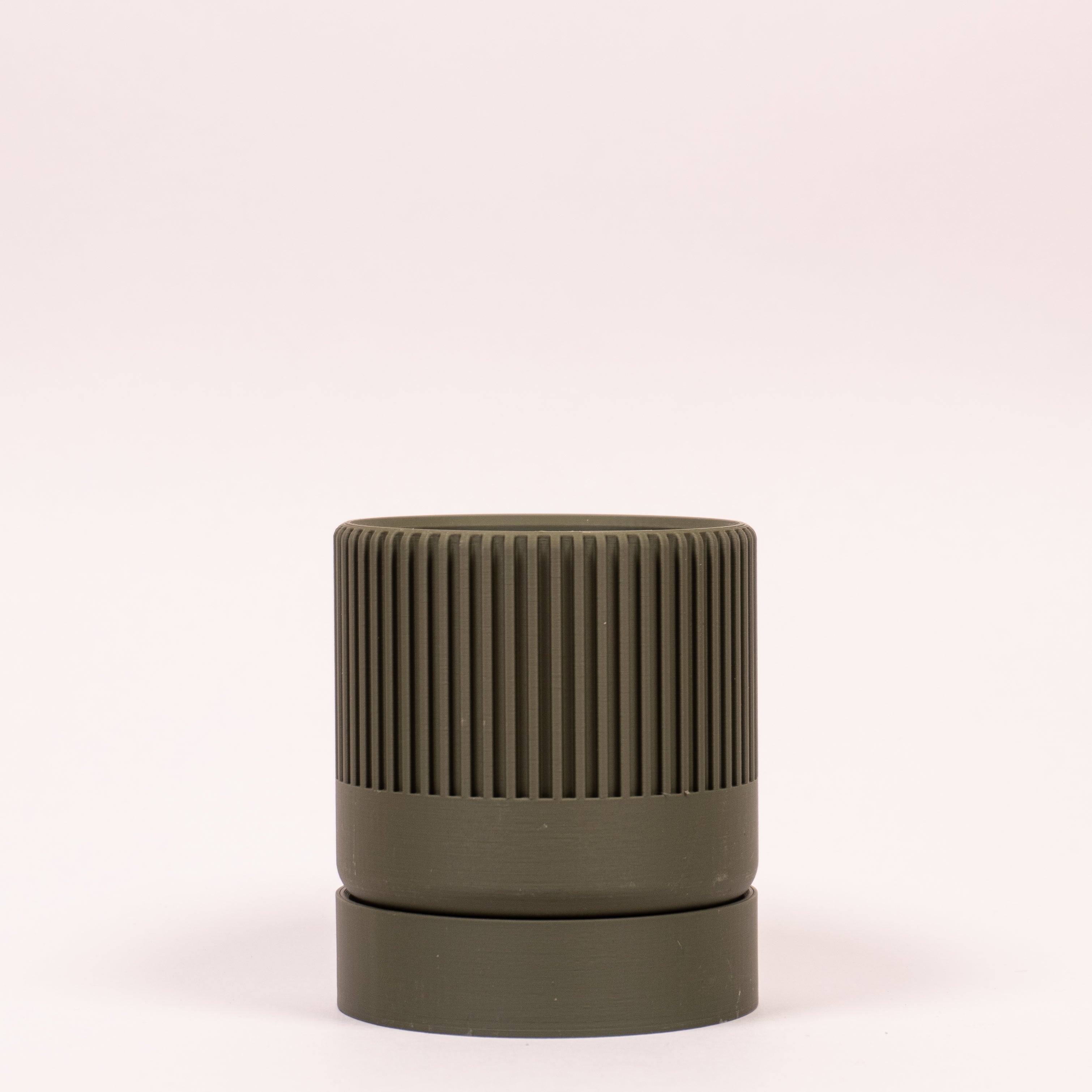 Billede af en grøn Seedling urtepotteskjuler Ø6cm stående oprejst i en ren billedboks med hvid baggrund. Viser det rolige design i bioplast.