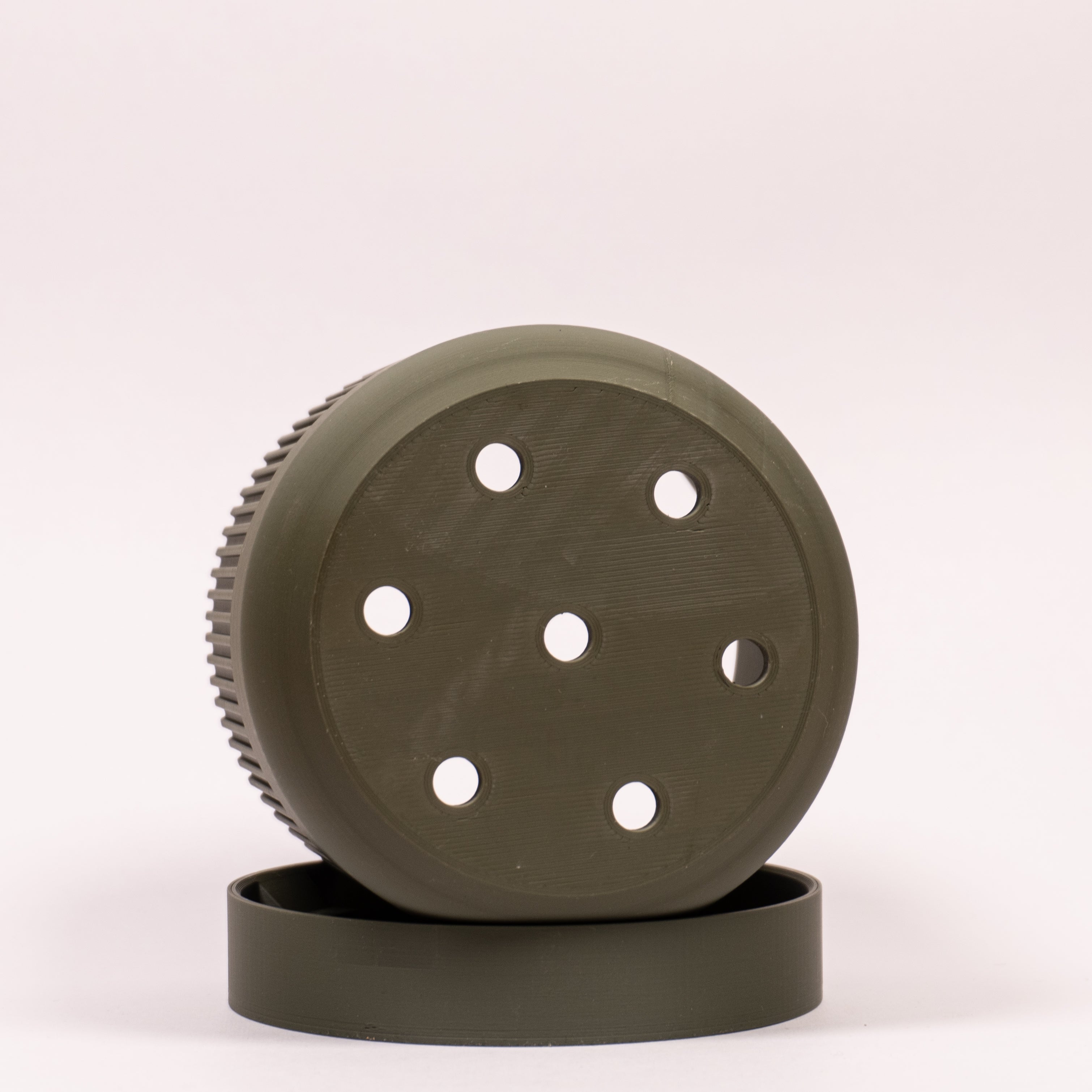 Foto af grøn Seedling urtepotteskjuler Ø9cm, placeret på siden i drypbakken, hvor de funktionelle drænhuller er synlige.