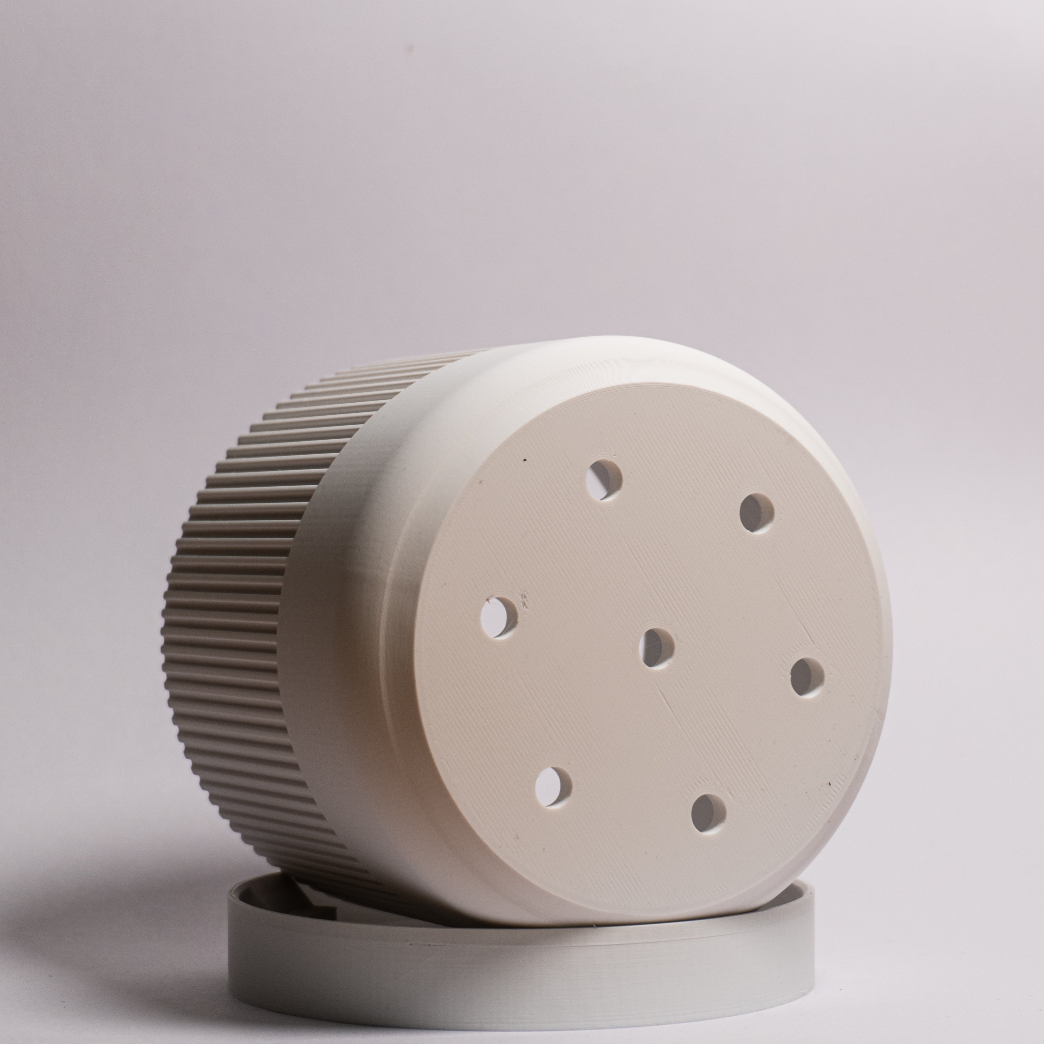 Nærbillede af hvid Seedling urtepotteskjuler Ø11cm på siden i drypbakken på hvid baggrund, hvor drænhullerne i bunden er synlige.