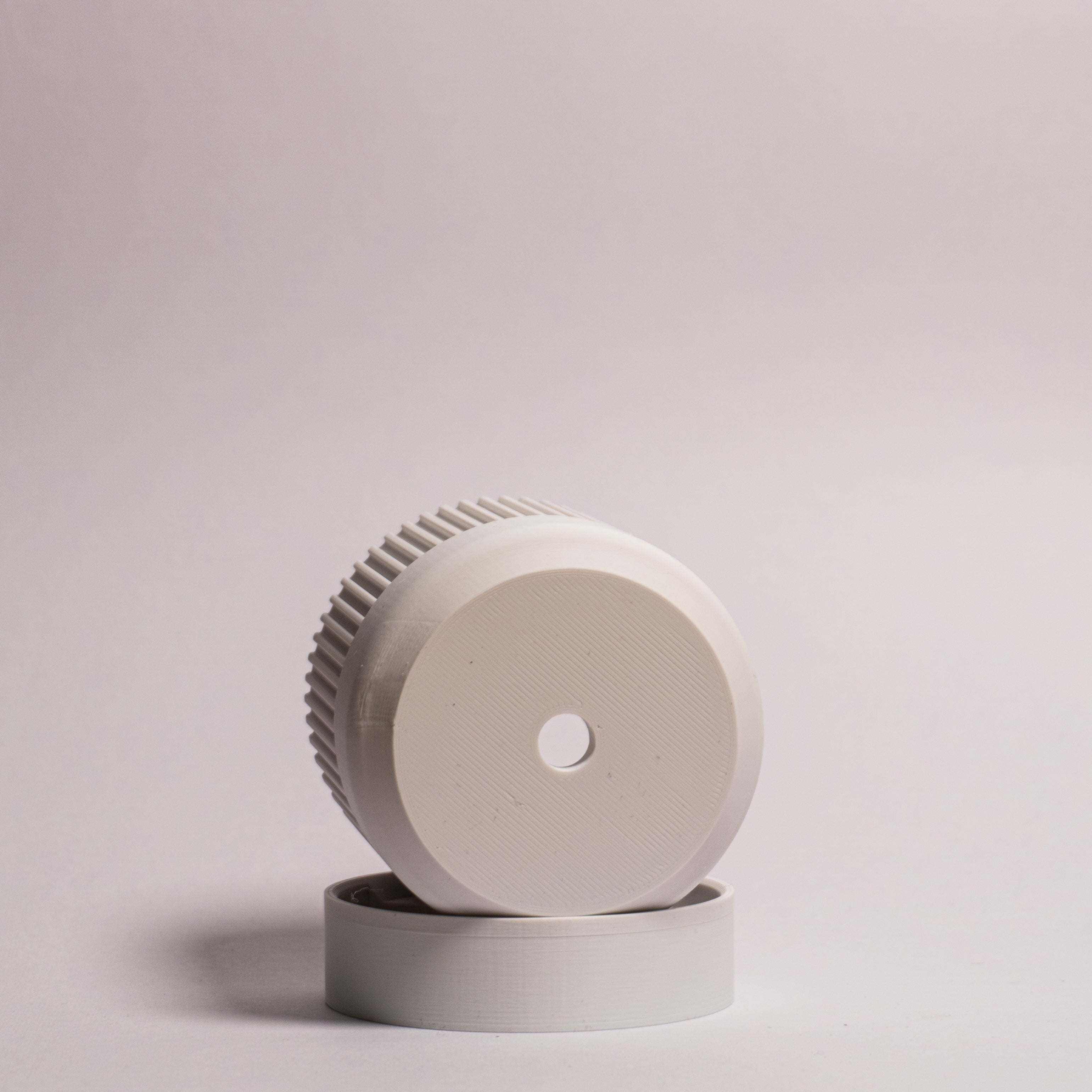 Nærbillede af en hvid Seedling urtepotteskjuler Ø6cm, lagt på siden i den matchende drypbakke på en hvid baggrund, der tydeligt viser drænhullerne i bunden.