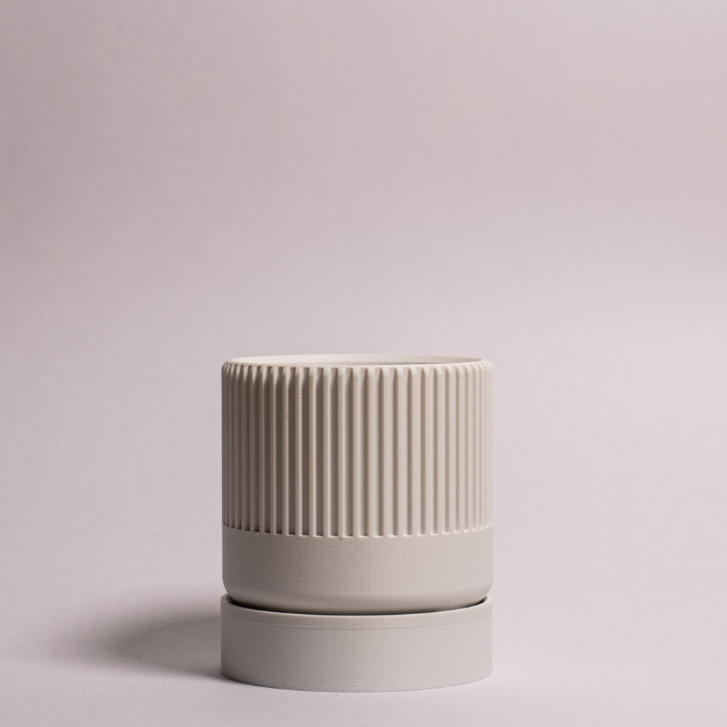 Billede af en hvid Seedling urtepotteskjuler Ø6cm stående oprejst i en ren billedboks med hvid baggrund. Viser minimalistisk design i bioplast.