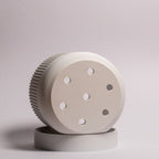 Foto af hvid Seedling urtepotteskjuler Ø9cm, drejet for at vise drænhullerne i bunden og den matchende drypbakke på hvid baggrund.