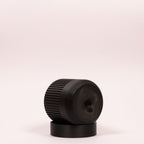 Nærbillede af sort Seedling urtepotteskjuler Ø6cm, lagt på siden i den sorte drypbakke, og viser tydeligt drænhullerne i bunden på hvid baggrund.