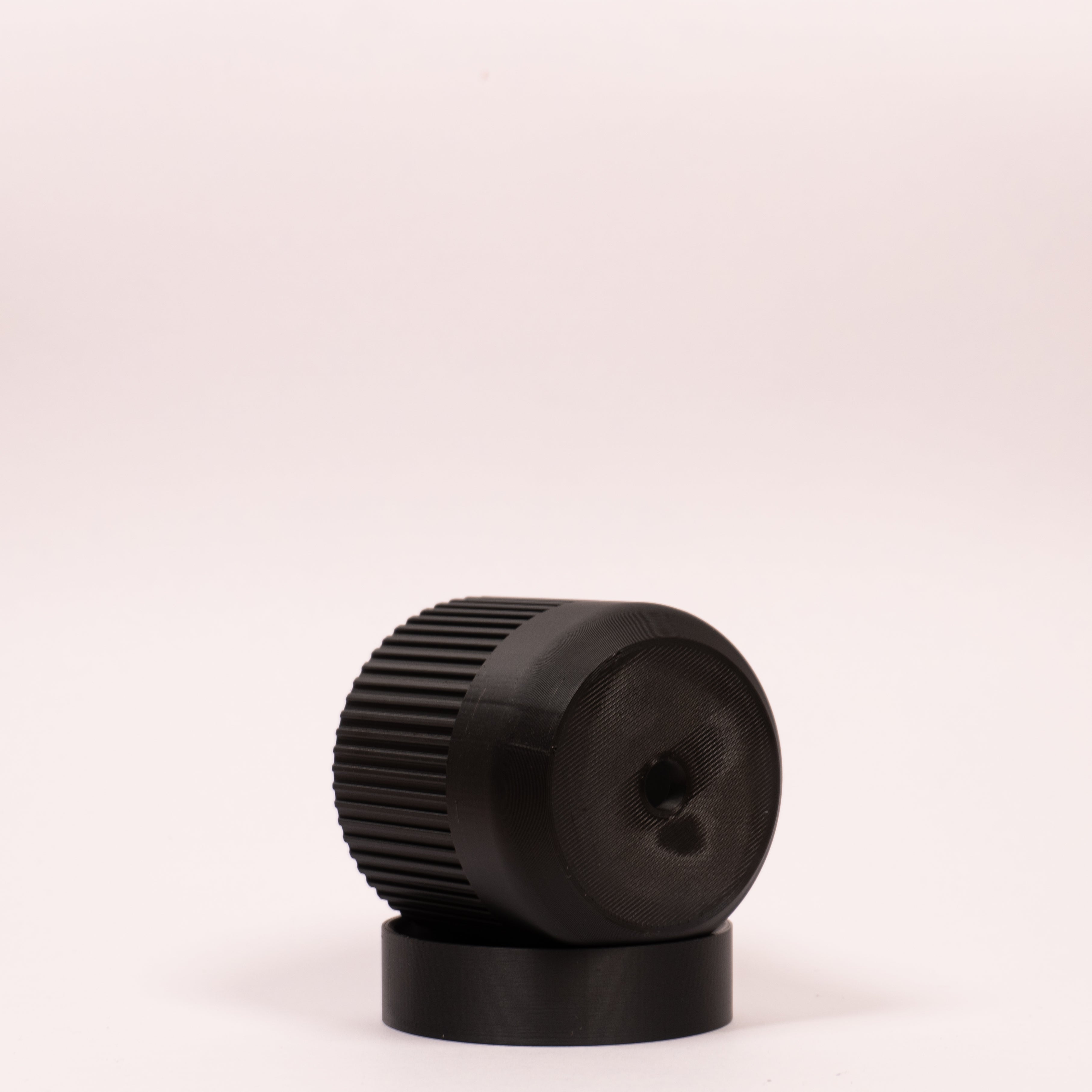 Nærbillede af sort Seedling urtepotteskjuler Ø6cm, lagt på siden i den sorte drypbakke, og viser tydeligt drænhullerne i bunden på hvid baggrund.