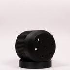 Foto af sort Seedling urtepotteskjuler Ø9cm, placeret på siden i drypbakken, hvor drænhullerne i bunden er synlige.